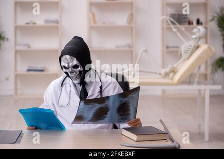 Devil doctor radiologist examining skeleton patient at the hospital Stock Photo