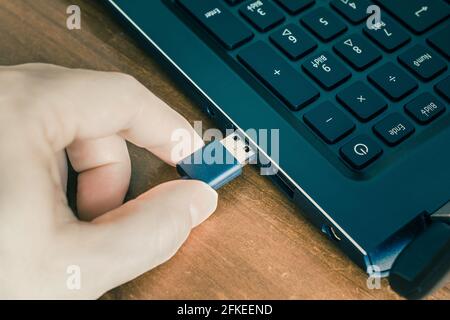 Male Hand Connecting A Black USB Cable To The USB Port Of A Black Notebook Stock Photo