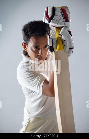 A batsman, Cricketer practicing with his bat in the dressing room Stock Photo