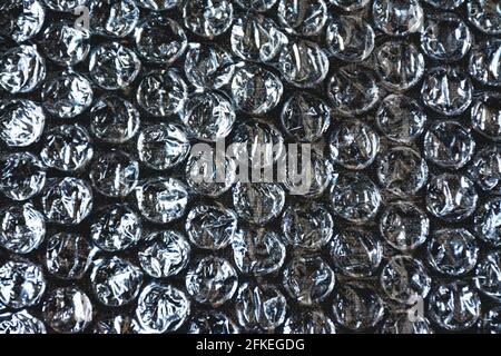 Transparent plastic film of bubbles on a textured dark cloth as background of designs Stock Photo