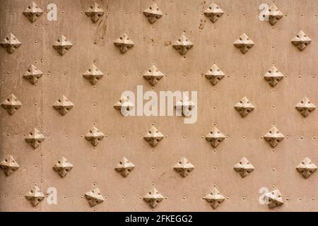 Old metal door with cross or diamond shaped decorated iron nails Stock Photo