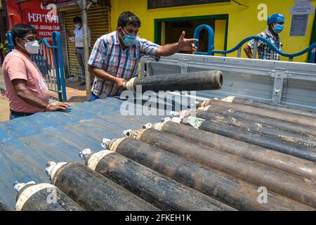 Employees of an oxygen refilling shop unloading oxygen cylinder from a ...