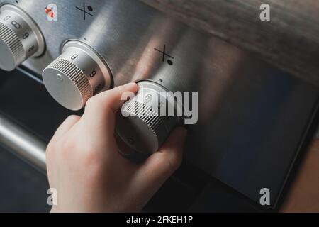 Hand Of A Child Switching On Stove Controls - Prevent Child Hazard Concept Stock Photo