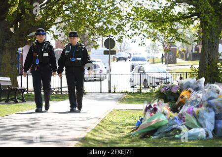 Police Community Support Officers walk past floral tributes in a park in Aylesham village close to the scene in Snowdown, Kent, where the body of PCSO Julia James was found. Picture date: Saturday May 1, 2021. Stock Photo