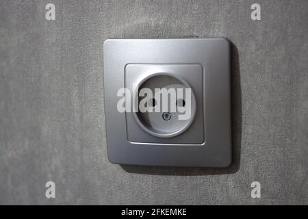 a gray electrical outlet on a gray concrete wall Stock Photo