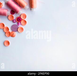 Border from a scattering of pink and coral buttons and spools of thread. Copy space for text. Stock Photo