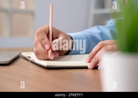 Asian Businessman Writing a business plan After looking at the annual profit and loss summary report.  The concept of Business success Needs to be ana Stock Photo