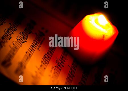 Music Notes Sheet in a Red Candle Light Photo Stock Photo