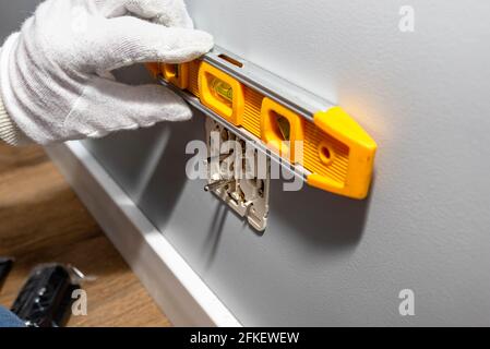 An electrician inserts a double grounded electrical outlet into the electrical box in the wall of the room, places the outlet using a spirit level. Stock Photo