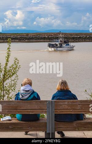 Two women seated on a bench along the Steveston waterfront in British Columbia Canada Stock Photo