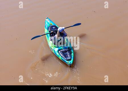 Overhead view of a woman in a kayak paddling in the muddy Fraser River during spring run-off with glacial and snow melt Steveston British Columbia Can Stock Photo