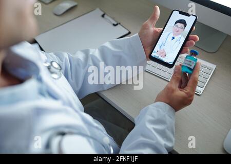 Chief physician video calling his colleague from another hospital to discuss new vaccine against coronavirus Stock Photo