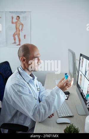 Chief physician of hospital having online conference with his colleagues and discussing new vaccine against coronavirus Stock Photo