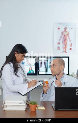 Doctors discussing new innovative medicine, supplement or painkiller when spending time in doctors lounge room Stock Photo