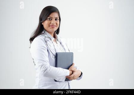 Pretty confident young Indian doctor posing with tablet computer against white background Stock Photo