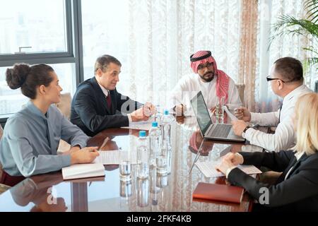 A group of delegates or businesspeople sitting around a table during meeting Stock Photo