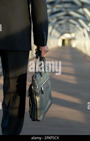 A person carrying black leather handbag in front of camera Stock Photo