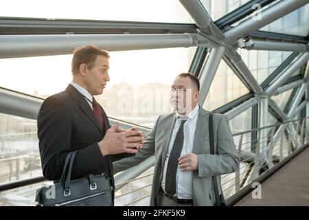 Two mature confident businessmen in suits talking in a server room Stock Photo