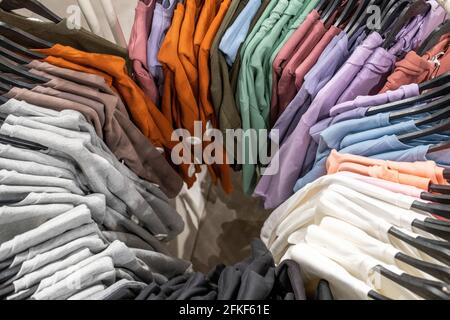 Variety of colorful clothes on hangers in store Stock Photo