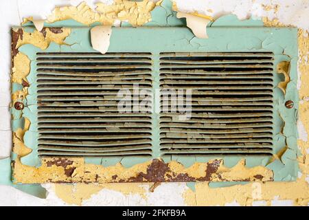 Old old air vent in an abandoned school. Paint is peeling around it, and metal is rusty. Stock Photo
