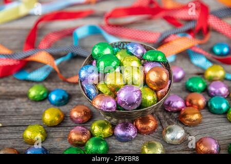 Multi-coloured foil covered chocolate. Foil covered gift chocolates wooden background. Candy feast. Eid al-Fitr (Feast of Ramadan) concept. Stock Photo