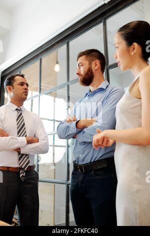 Frowning confident Indian entrepreneur talking to colleagues at meeting and asking about work of their departments Stock Photo
