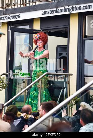 Brighton UK 1st May 2021 - A drag queen entertains outside a Brighton seafront bar as people enjoy the May Bank Holiday weekend with things gradually getting back to normal in England with lockdown restrictions allowing hospitality venues to serve drink outdoors : Credit Simon Dack / Alamy Live News Stock Photo