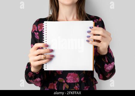 Young adult woman in dress holds blank open notepad Stock Photo