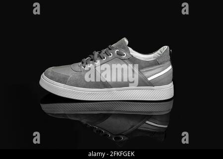 Grey casual sports shoes, sneaker isolated on a black background Stock Photo