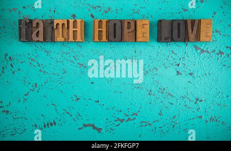 Faith Hope and Love Spelled in Wooden Type Set Block Letters on a Turquoise Background Stock Photo