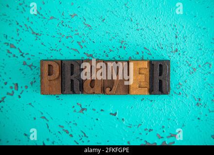 Prayer Spelled in Wooden Type Set Block Letters on a Turquoise Background Stock Photo