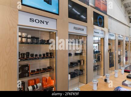 Camera store interior with shop display of cameras and lenses in cabinets of different camera brands: Sony, FujiFilm, Panasonic & Olympus brands Stock Photo