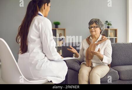 Old senior woman patient talking to doctor nurse caregiver sitting on home sofa Stock Photo