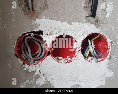 Electrical wires with cables at home repair. New electrical outlets. Socket on concrete wall Stock Photo