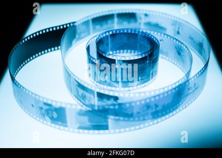 Analog black and white 35mm negative film strip on light table, blue tint Stock Photo