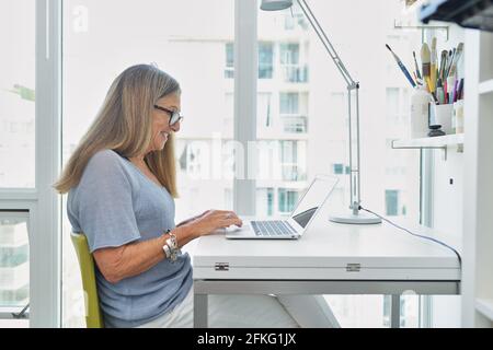 Attractive senior woman working on computer at desk Stock Photo