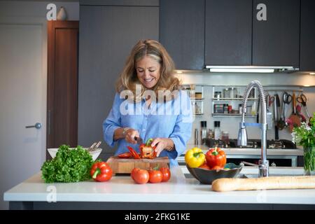 Senior older woman chopping vegetables in modern kitchen Stock Photo