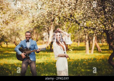 cheerful young couple. man plays guitar and girl dancing Stock Photo