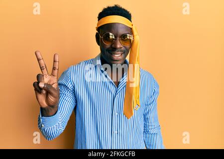 Handsome black man drunk wearing tie over head and sunglasses showing and pointing up with fingers number two while smiling confident and happy. Stock Photo