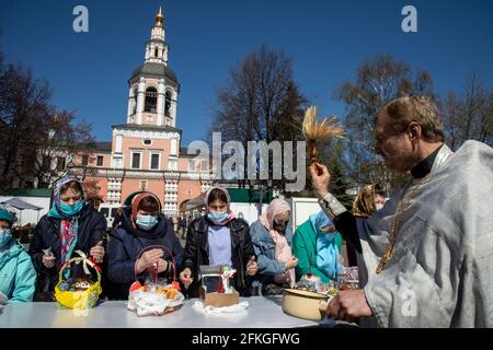 Moscow, Russia. 1st of May, 2021 An Orthodox priest blesses cakes and eggs on the eve of Orthodox Easter at the Danilov Monastery in Moscow, Russia. Since 1983, Danilov Monastery has functioned as the headquarters of the Russian Orthodox church and the official residence of the Patriarch of Moscow and all the Russia Stock Photo