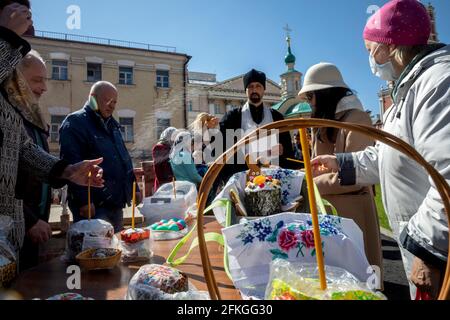 Moscow, Russia. 1st of May, 2021 An Orthodox priest blesses cakes and eggs on the eve of Orthodox Easter at the Vysokopetrovsky Monastery in Moscow, Russia. It is the male stauropegion monastery of the Russian Orthodox Church in Moscow; located in the city center at descends towards the Kremlin on Petrovka Street Stock Photo