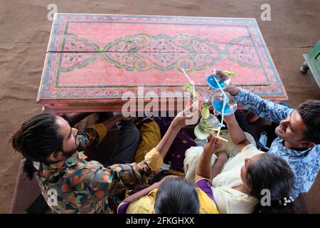 High angle shot of cheerful young Indian friends having fun in a cafe clinking cocktail glasses Stock Photo