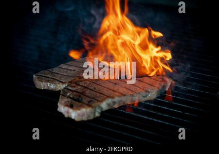 Two pieces of Striploin beef tips on getting grilled on a barbeque grill. Stock Photo