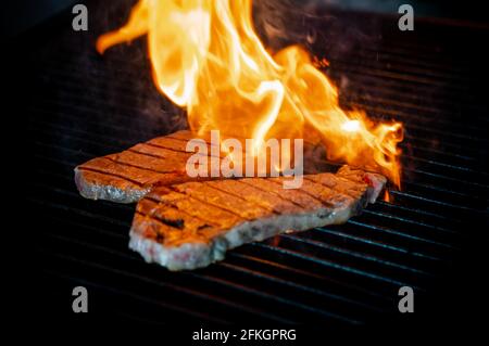 Two pieces of Striploin beef tips on getting grilled on a barbeque grill. Stock Photo