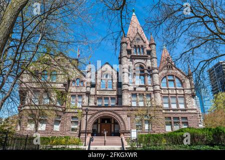 Victoria College in the grounds of the University of Toronto, Canada. The building has a Romanesque Revival architecture in red sandstone walls Stock Photo