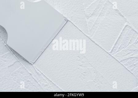 Interior finishing works, spatula applying white putty on the wall, copy space Stock Photo