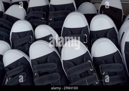 A heap of  black Kids sneakers Gumshoes Unbranded modern new in low price sport shoes. Fashion for Children kids, heap in market rubber shoes patchwor Stock Photo