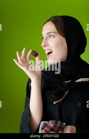 Young muslim girl wearing traditional muslim clothes holding dried dates Stock Photo