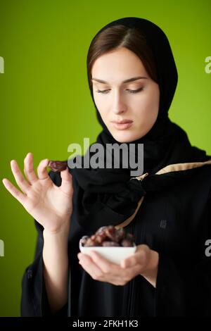 Young muslim girl wearing traditional muslim clothes holding dried dates Stock Photo