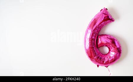 Foil balloon number 6 on white background, pink numeral Six made as inflatable shape for party. Flying figure 6 and copy space for text. Concept of in Stock Photo